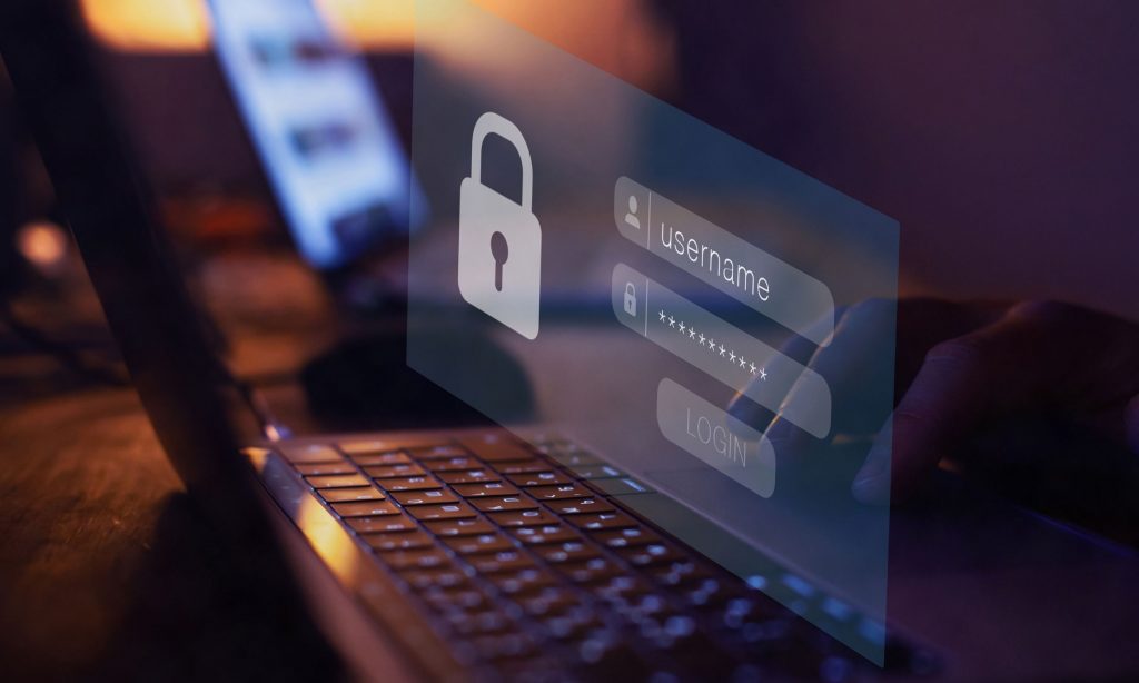 Cybersecurity concept showing login screen with username and password fields and a security padlock icon on a laptop.