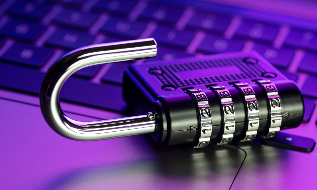 An open combination padlock resting on a laptop keyboard, symbolising a data breach and compromised security.