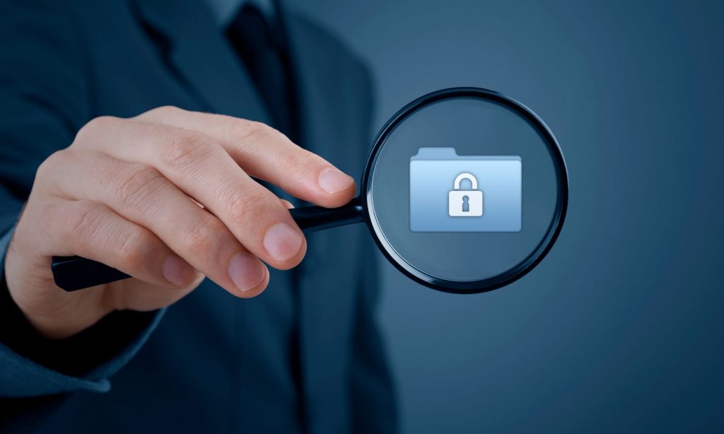 Magnifying glass over a secure folder icon representing data discovery and visibility in cybersecurity.