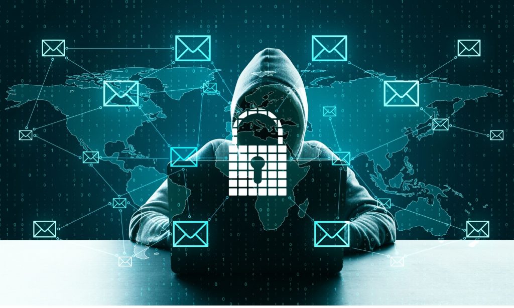 A hooded hacker at a laptop surrounded by phishing email icons and a digital padlock symbol, representing ransomware and data exfiltration threats.